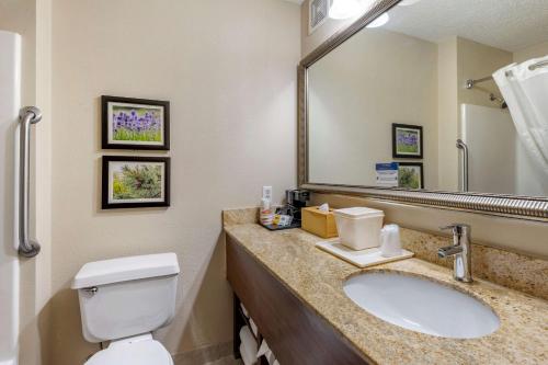 une salle de bain avec toilettes, lavabo et miroir dans l'établissement Comfort Inn & Suites Kelso - Longview, à Kelso