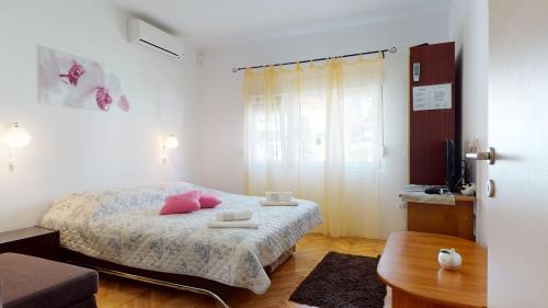 una camera da letto con un letto con cuscini rosa e un tavolo di Villa Ivanišević a Omiš (Almissa)