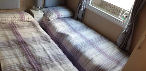 two beds in a small room with a window at Seldongoldengates in Kinmel Bay
