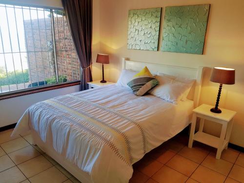 ein Schlafzimmer mit einem großen weißen Bett mit zwei Lampen in der Unterkunft Zinkwazi Beach townhouse in Zinkwazi Beach