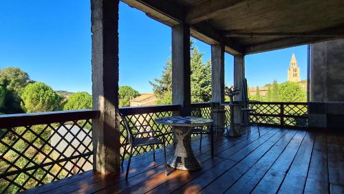 - une terrasse couverte avec une table et une vue sur une église dans l'établissement Campus Vivendi Studio, à Montagnac