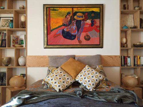 una camera da letto con un dipinto sopra un letto con cuscini di Les 3 Koïs a Riec-sur-Bélon