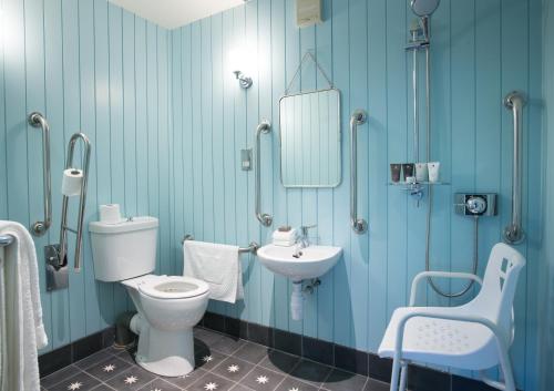 a blue bathroom with a toilet and a sink at The Swan Hotel in Southwold