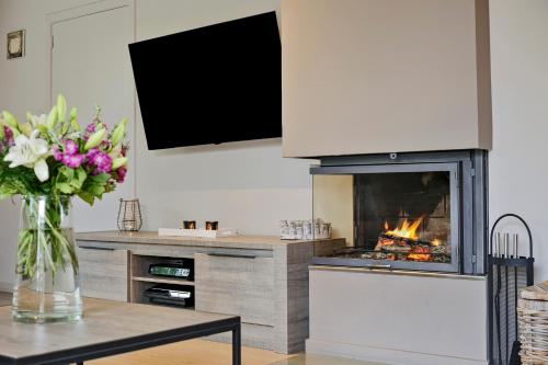 a living room with a fireplace and a table with flowers at Vakantievilla met luxe en sauna in duinenreservaat in Koksijde