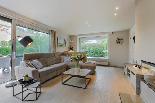 a living room with a couch and a table at Vakantievilla met luxe en sauna in duinenreservaat in Koksijde