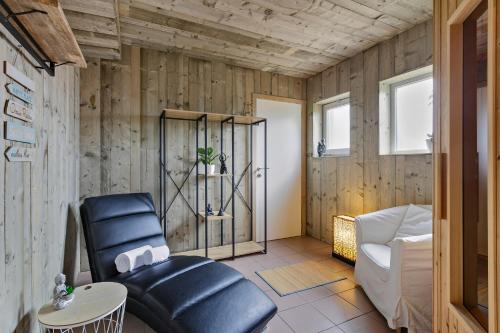 a living room with wooden walls and a black leather chair at Vakantievilla met luxe en sauna in duinenreservaat in Koksijde