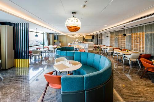 un restaurant avec un canapé bleu, des tables et des chaises dans l'établissement Atour Hotel Guangzhou Huadu Financial Center, à Huadu