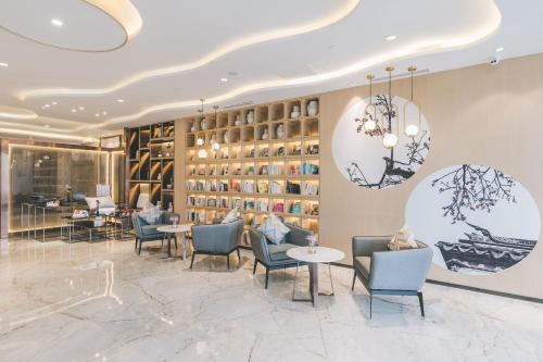 een restaurant met stoelen en tafels en een muur van boeken bij Atour Hotel Kunshan Yongda Business Plaza in Kunshan