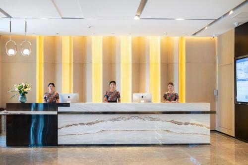 three people sitting at a counter with their laptops at Atour Hotel Jining Lingxiu City Plaza in Jining