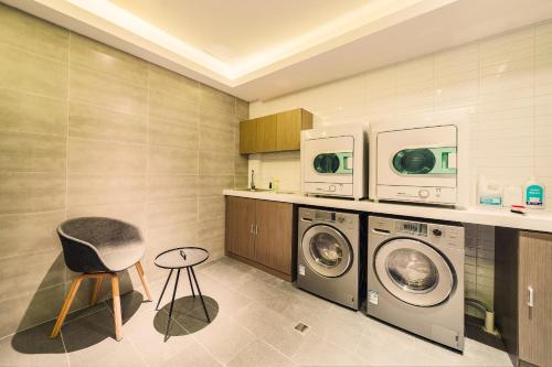 a laundry room with two washing machines and a chair at Atour Light Harbin Central Street in Harbin