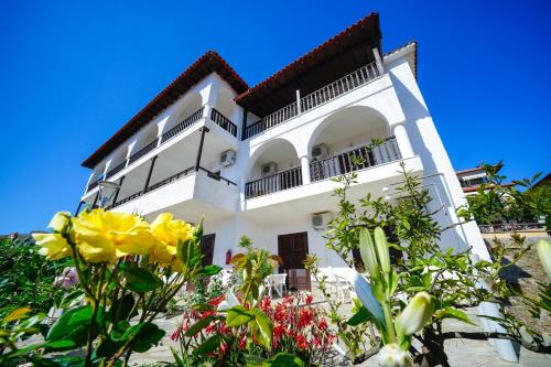 a white building with flowers in front of it at Kritikos Apartments in Pyrgadikia