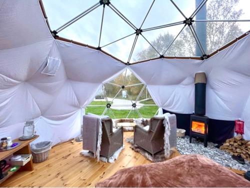 a room with a tent with two chairs and a fireplace at Wild Caribou Dome in Lakselv