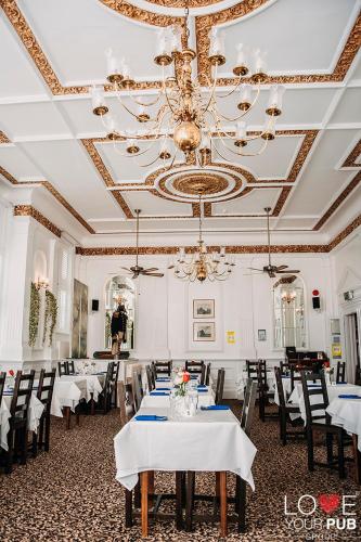 a dining room with white tables and chairs and a chandelier at Keppels Head Hotel in Portsmouth