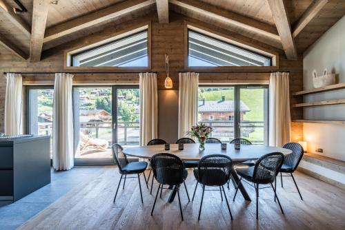 une salle à manger avec une table, des chaises et des fenêtres dans l'établissement Apartment Merbau Les Gets - by EMERALD STAY, aux Gets