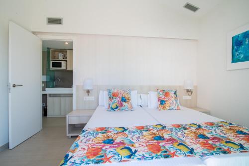 una camera da letto con un grande letto bianco con cuscini colorati di Hotel LIVVO Dunagolf Suites a Maspalomas