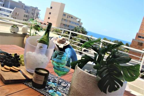 德班的住宿－Luxury Apartment in Umhlanga Rocks，阳台上的桌子上摆放着一瓶葡萄酒和玻璃杯
