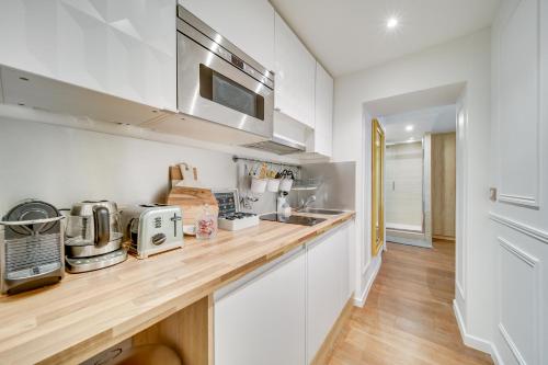 - une cuisine avec des murs blancs et un comptoir en bois dans l'établissement Central Historical Studio by Architect - Louvre, à Paris