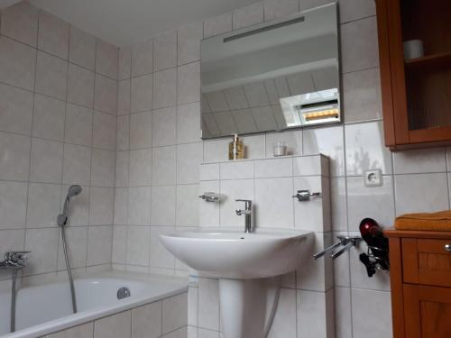 a bathroom with a sink and a tub and a mirror at Ferienwohnung Vor den Toren Lübecks in Herrnburg