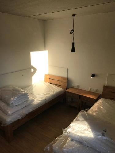 two beds in a room with a window and two tables at SITE.INN Hamburg in Hamburg