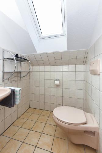 a bathroom with a toilet and a sink and a skylight at Hotel-Pension Altes Siel in Bensersiel