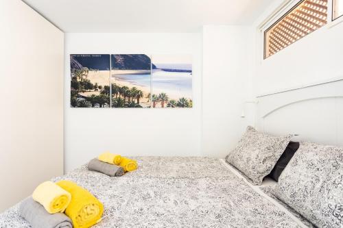 a white bedroom with a bed with yellow and gray pillows at Apartment Royal Sunset Loggia in Palm-Mar