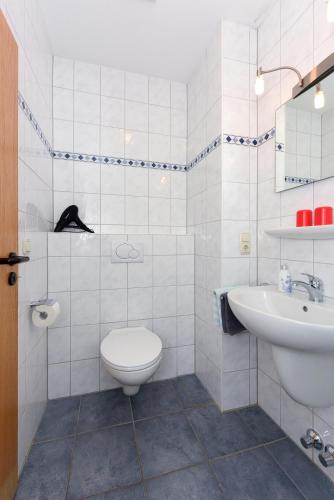a white bathroom with a toilet and a sink at Hotel-Pension Altes Siel in Bensersiel