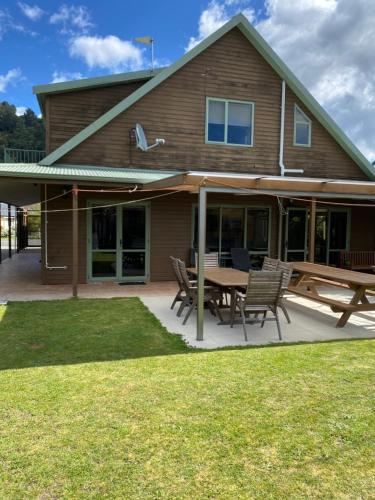 a house with a picnic table and chairs in front of it at Abel Tasman Marahau in Marahau