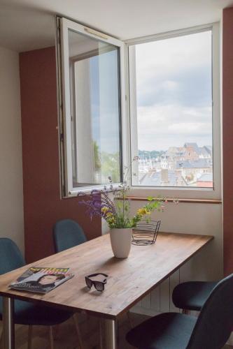 une table avec un vase de fleurs et une fenêtre dans l'établissement Appartement de 60m2 à 2 pas du port de Paimpol, à Paimpol