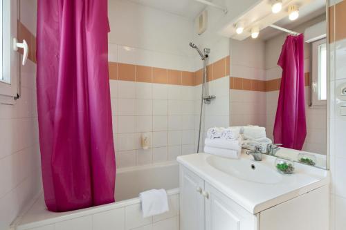ディジョンにあるAppart'City Classic Dijon - Toison D'Orのピンクのシャワーカーテンとシンク付きのバスルーム