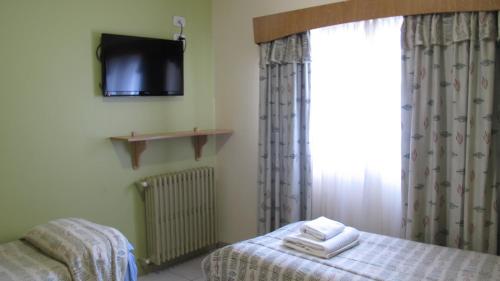 a bedroom with a bed and a tv on the wall at Hotel Internacional in San Carlos de Bariloche