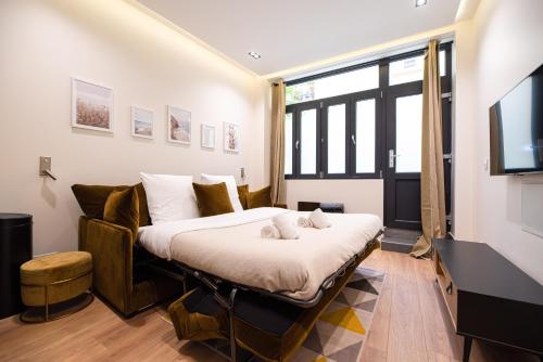 een slaapkamer met een bed met een bank en een televisie bij MBM - TERRAGE in Parijs