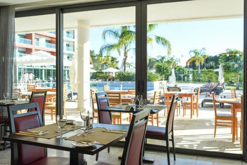 a restaurant with tables and chairs and a view of the water at Aquashow Park Hotel in Quarteira