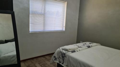 a white room with a bed and a window at Platinum Apartment in Polokwane