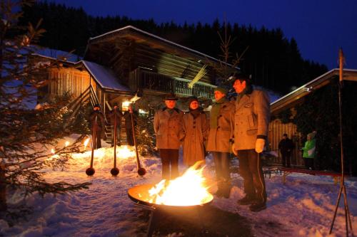 a group of people standing around a fire in the snow at Naturhotel Hüttenwirt im Grossarltal in Hüttschlag