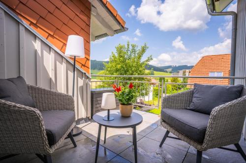 a patio with two chairs and a table with flowers at MINAROSO appartements am badeparadies in Titisee-Neustadt