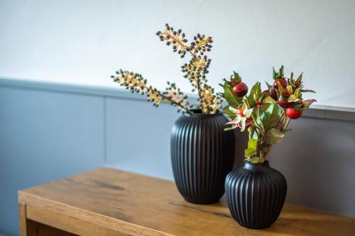 two black vases sitting on a wooden table with flowers at MINAROSO appartements am badeparadies in Titisee-Neustadt