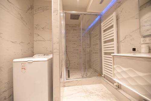 La salle de bains blanche est pourvue d'une douche et d'un réfrigérateur. dans l'établissement MBM - LA TOUR, à Paris