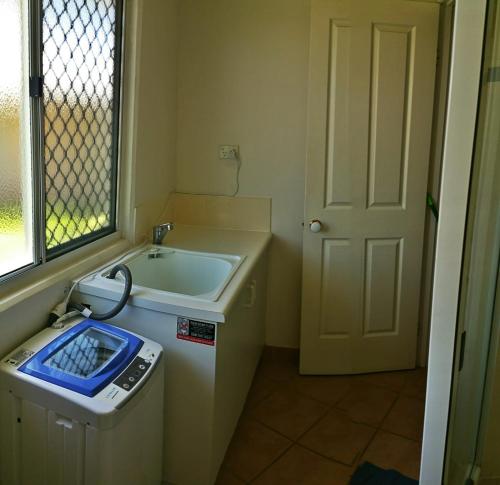 Sea View Villa. 2 bedroom. Sleeps 4. Free WIFI في Victoria Park: حمام صغير مع مغسلة وغسالة ملابس