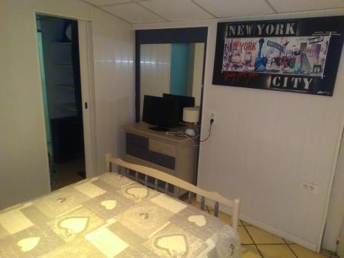 Un pequeño dormitorio con una cama y un televisor. en Studios - Bord de Plage, en Vias