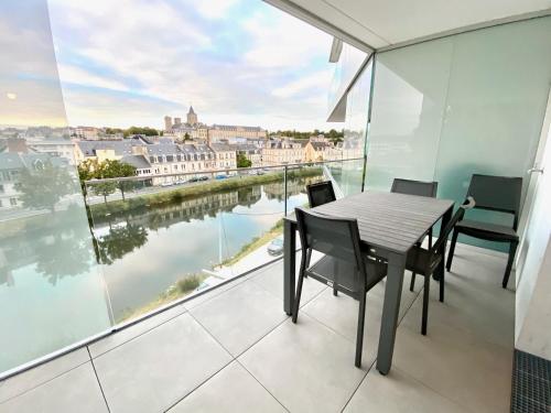 een tafel en stoelen op een balkon met uitzicht op het water bij Venus YourHostHelper in Caen