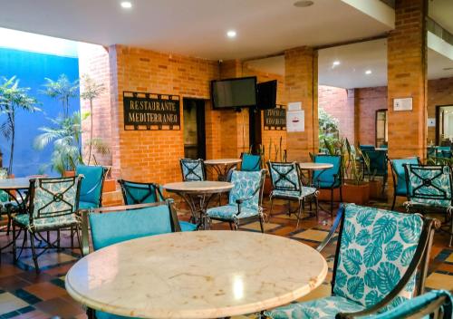 a dining room with tables and chairs and a tv at Hotel Internacional La Triada in Bucaramanga