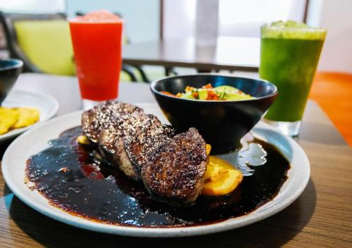 a plate of food with steak and a bowl of fruit at Hotel Internacional La Triada in Bucaramanga