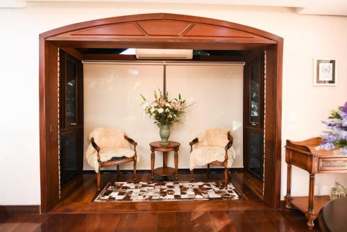 two chairs and a table with a vase of flowers at Hotel Kehl Haus in Gramado