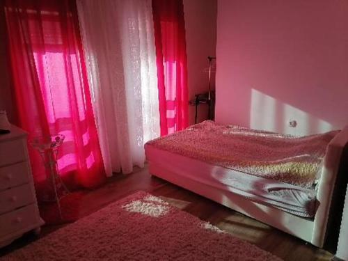 Habitación de color rosa con cama y ventana en Dreams Apartments, en Niš