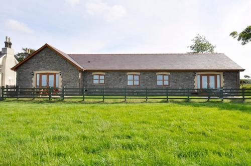 een stenen huis met een hek in een veld bij Blaengader Cottages DINAS in Aberystwyth