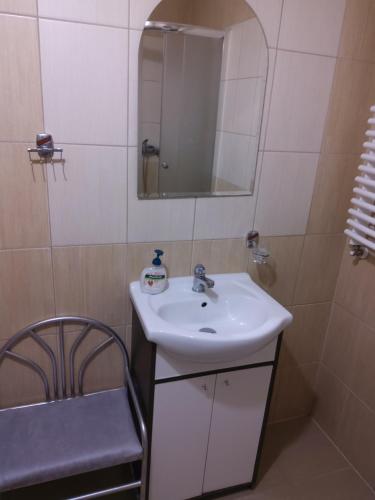 een badkamer met een wastafel, een spiegel en een stoel bij Pokoje gościnne Sobieszow in Jelenia Góra