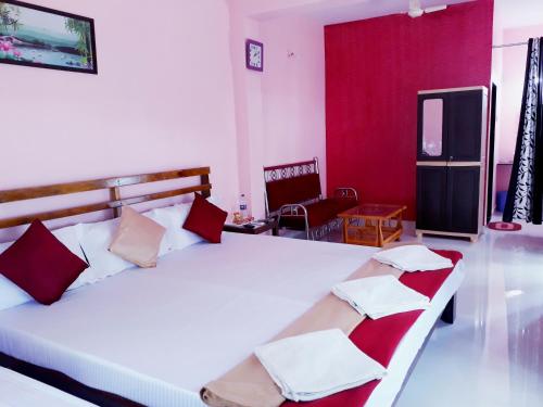 a bedroom with a large white bed with red walls at Samant Beach Resort in Malvan
