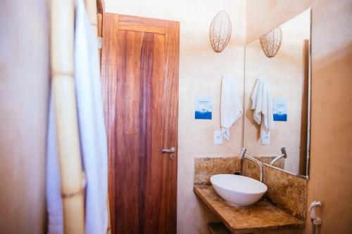 a bathroom with a sink and a wooden door at CasaLô Hotel in Jericoacoara