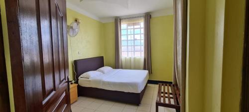 niewielka sypialnia z łóżkiem i oknem w obiekcie DESA HOMES w mieście Voi