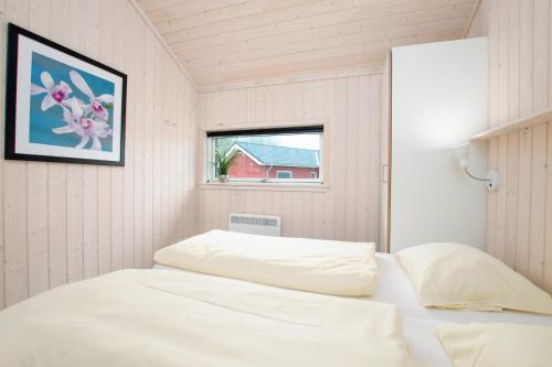ein weißes Bett in einem Zimmer mit Fenster in der Unterkunft Resort 2 Ocean Cottage A 77 in Großenbrode